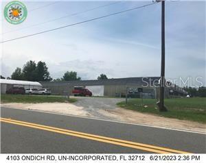 A long, single-story industrial building sits behind a gravel driveway next to a paved road — 4103 ONDICH ROAD, APOPKA, FL