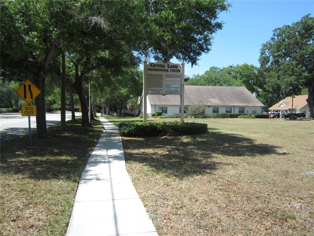 A sign for Crystal Lakes Professional Center stands beside a sidewalk and a grassy lawn — 209 CRYSTAL GROVE BOULEVARD, LUTZ, FL
