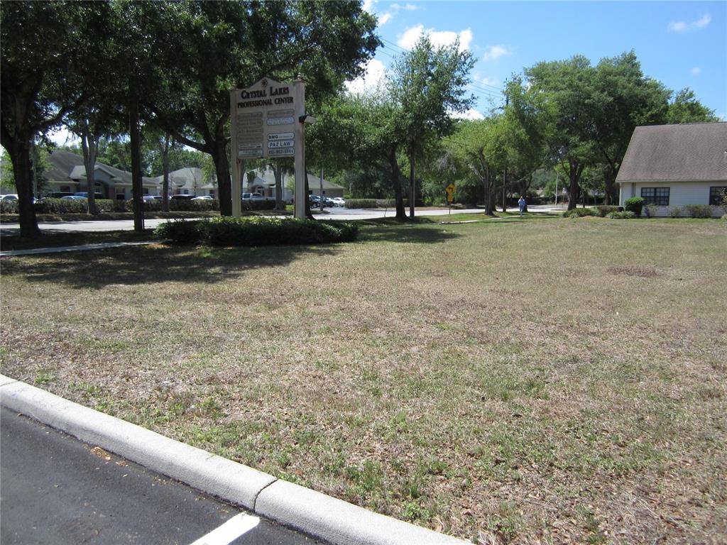 A sign for Crystal Lakes Professional Center stands on a grassy lot near a building — 209 CRYSTAL GROVE BOULEVARD, LUTZ, FL