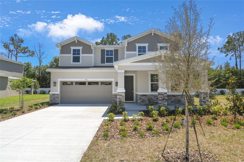 A two-story suburban house features a stone-accented facade, a two-car garage, and a front porch — 3716 DEER RIDGE DRIVE, MOUNT DORA, FL