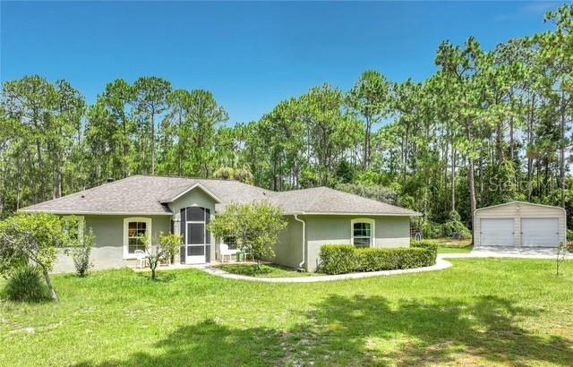 A single-story house with a gray exterior and a detached two-car garage sits on grass — 41821 ROYAL TRAILS ROAD, EUSTIS, FL