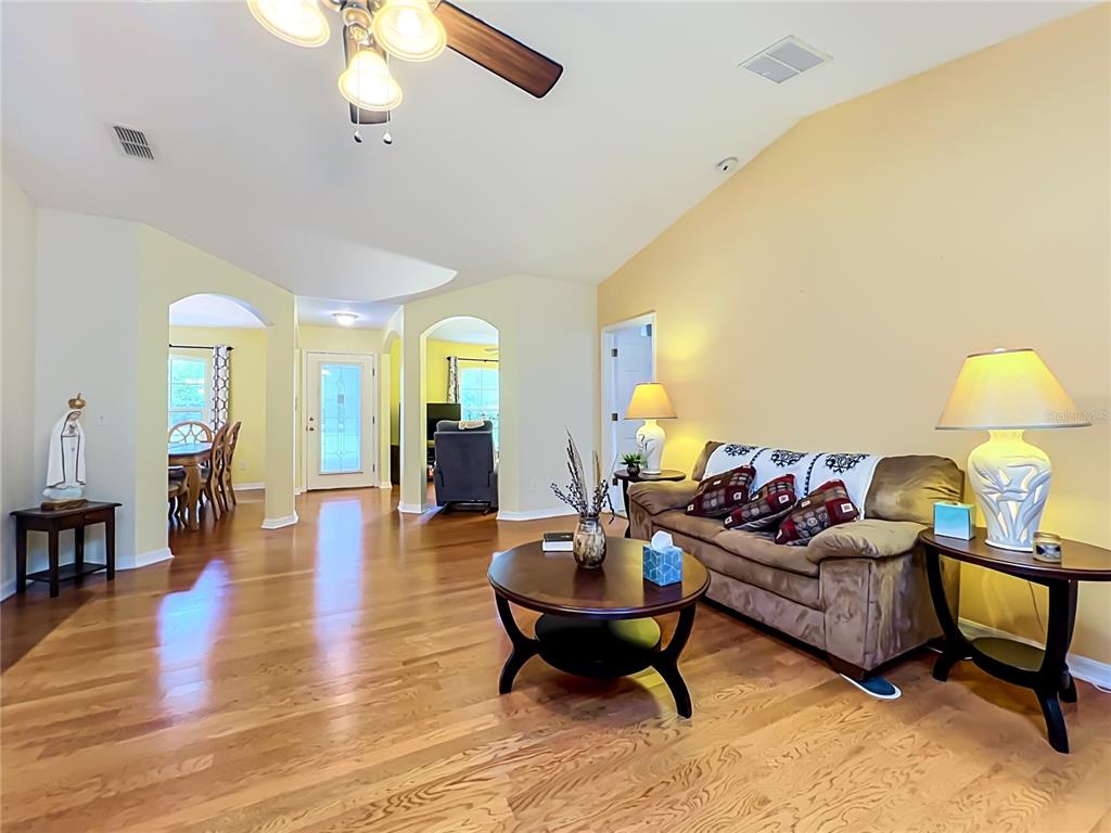 A living room with hardwood floors, a brown sofa, and a vaulted ceiling — 41821 ROYAL TRAILS ROAD, EUSTIS, FL
