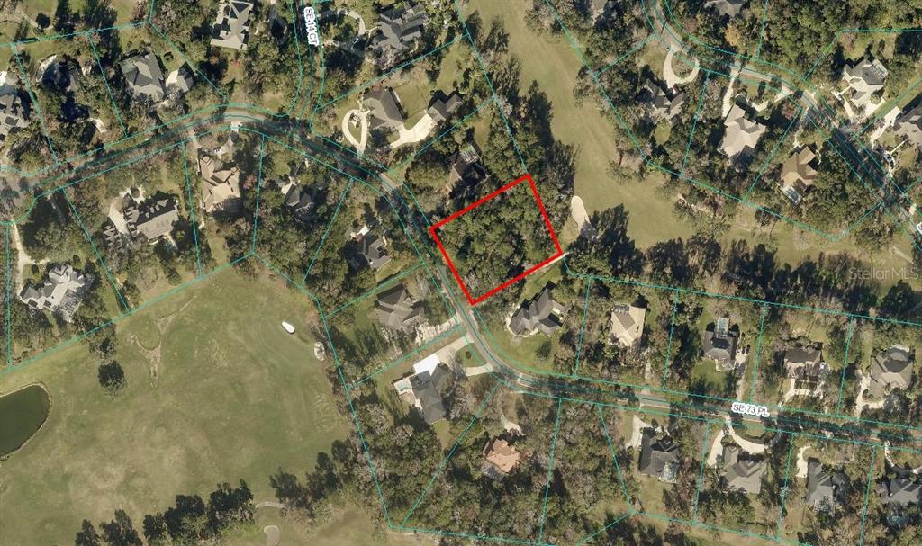 An aerial view shows a vacant, wooded residential lot outlined in red within a neighborhood — 1555 SE 73RD PLACE, OCALA, FL
