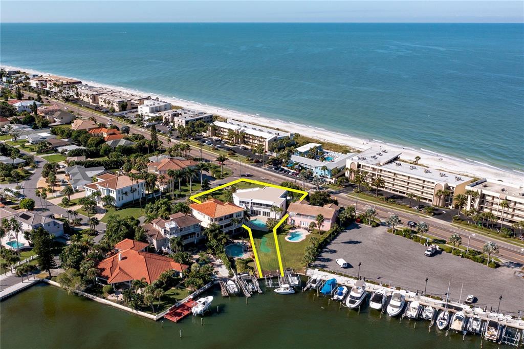 An aerial view shows a waterfront property with a pool, dock, and boat slips — 101 HARRISON AVENUE, BELLEAIR BEACH, FL
