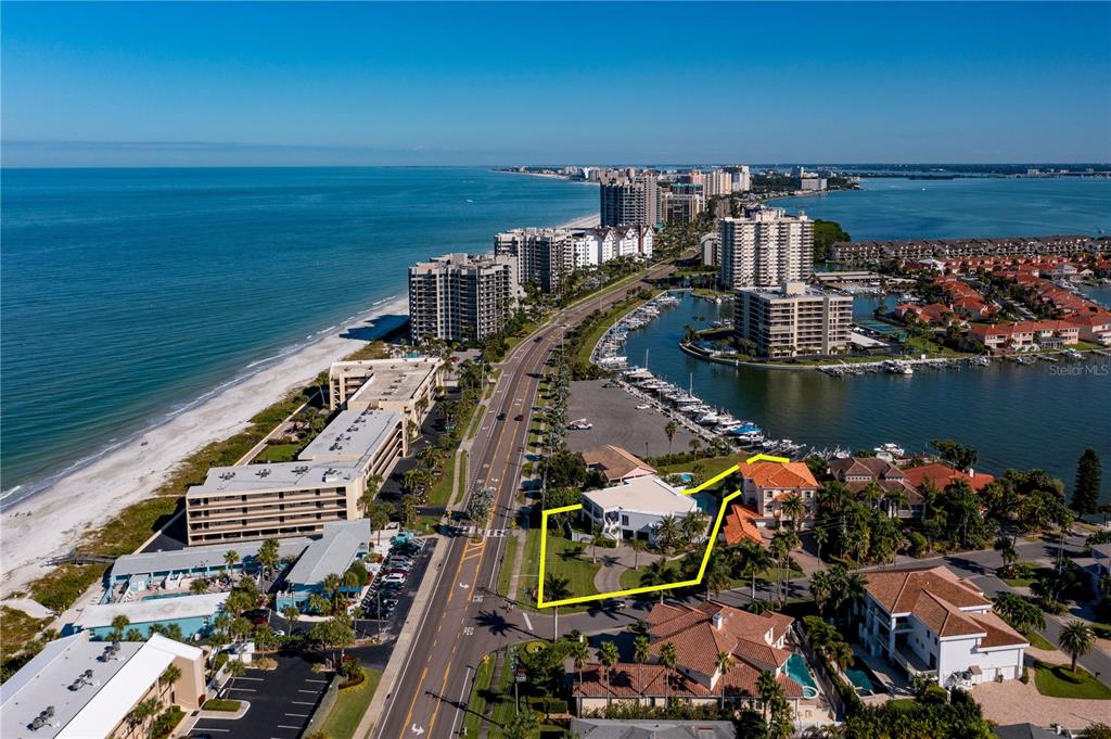 An aerial view shows a coastal property outlined in yellow near a beach and marina — 101 HARRISON AVENUE, BELLEAIR BEACH, FL
