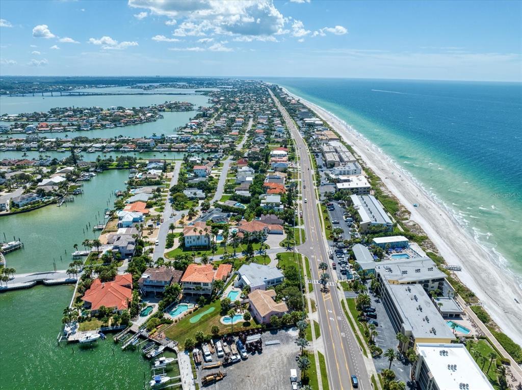 An aerial view shows a coastal neighborhood with houses, a road, and a sandy beach — 101 HARRISON AVENUE, BELLEAIR BEACH, FL