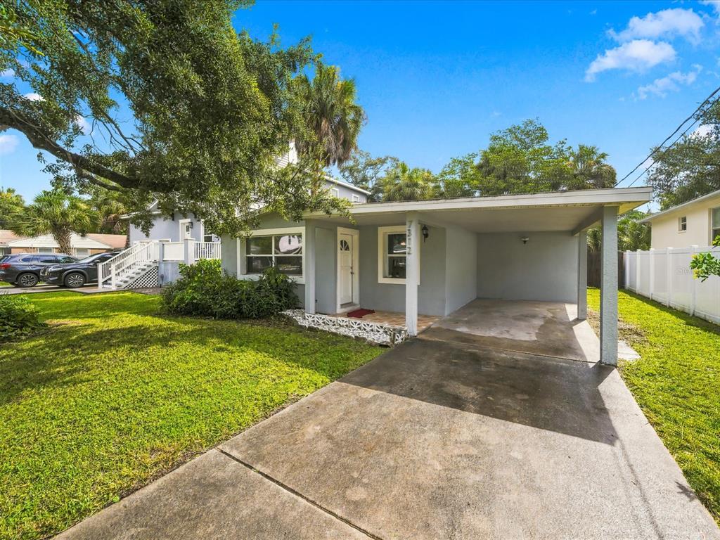 A gray single-story house with a carport, a concrete driveway, and a large front lawn — 7312 S ELLIOTT STREET, TAMPA, FL