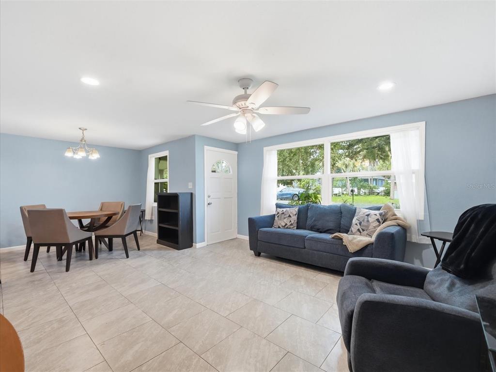 A living and dining area with light blue walls, tile flooring, and a ceiling fan — 7312 S ELLIOTT STREET, TAMPA, FL