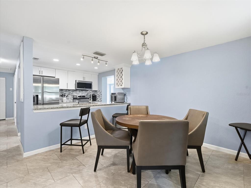 A dining area with a round table and chairs sits adjacent to an open kitchen — 7312 S ELLIOTT STREET, TAMPA, FL