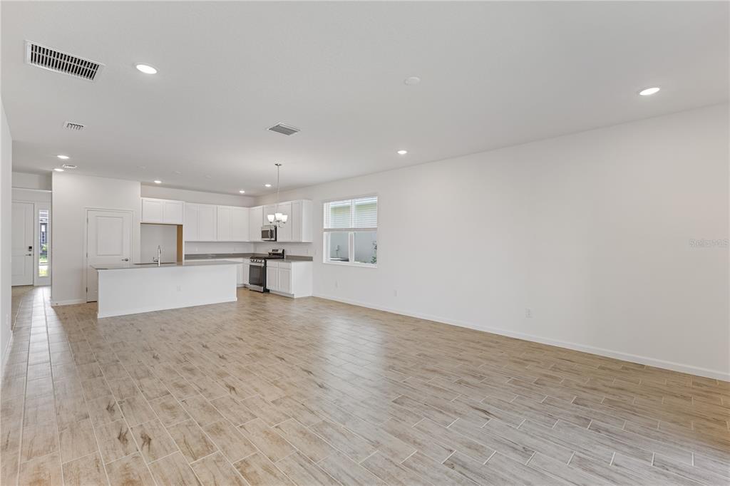 An open-concept kitchen and living area features white cabinetry, a kitchen island, and tile flooring — 2240 SIRENA LANE, MOUNT DORA, FL