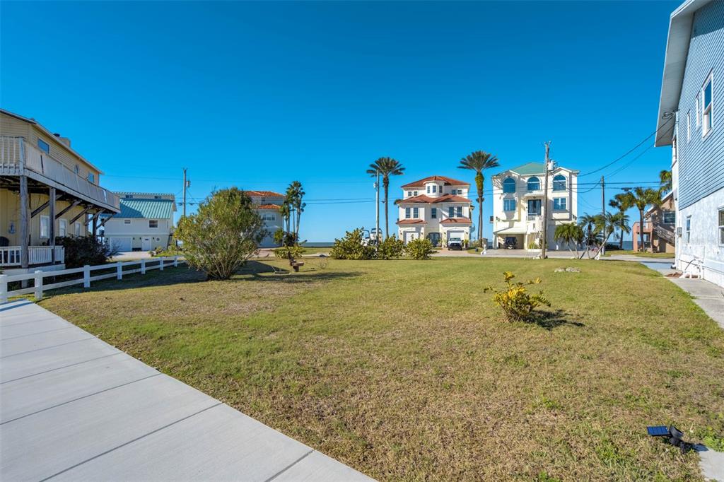 A grassy yard sits between two houses with a view of the ocean in distance — 6424 DRIFTWOOD DRIVE, HUDSON, FL