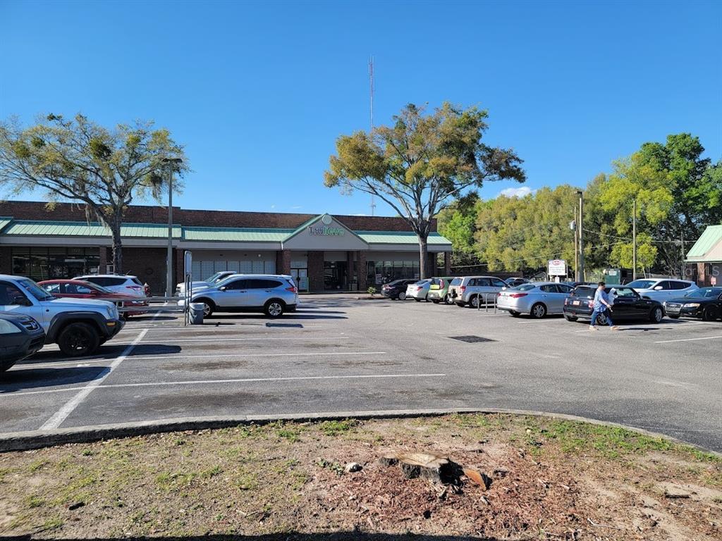 A parking lot sits in front of a commercial building with a green awning — 1927 SW COLLEGE ROAD UNIT A, OCALA, FL