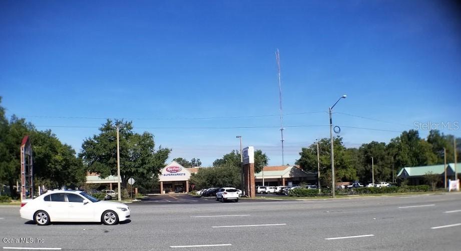 A white sedan drives past a shopping center with a Key Food supermarket sign — 1927 SW COLLEGE ROAD UNIT A, OCALA, FL