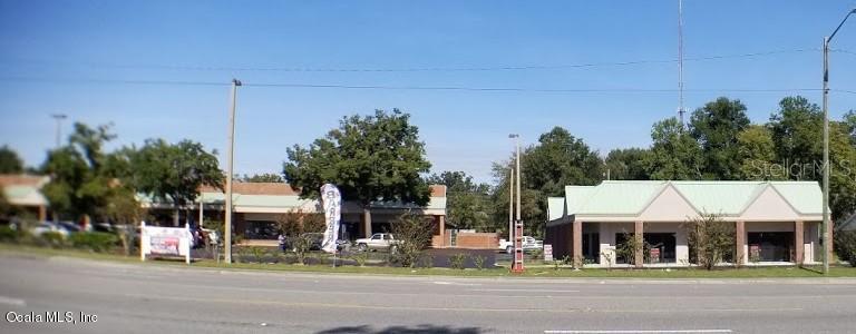 A view of a commercial strip mall with a parking lot and trees — 1927 SW COLLEGE ROAD UNIT A, OCALA, FL