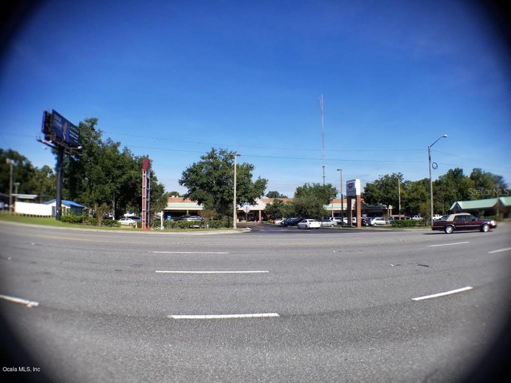 A wide-angle view of a commercial parking lot and building exterior under a clear sky — 1927 SW COLLEGE ROAD UNIT A, OCALA, FL