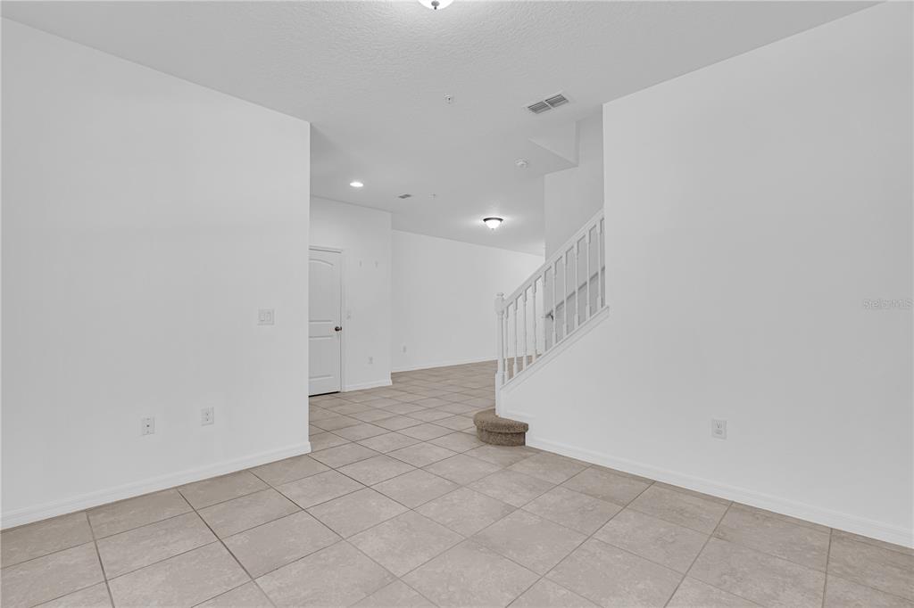 An interior view shows a tiled room with a staircase and a white door — 4450 CAPITAL BOULEVARD, ST CLOUD, FL