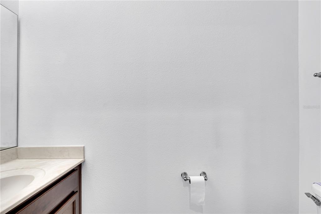 A bathroom features a dark wood vanity with a light countertop and a toilet paper holder — 4450 CAPITAL BOULEVARD, ST CLOUD, FL