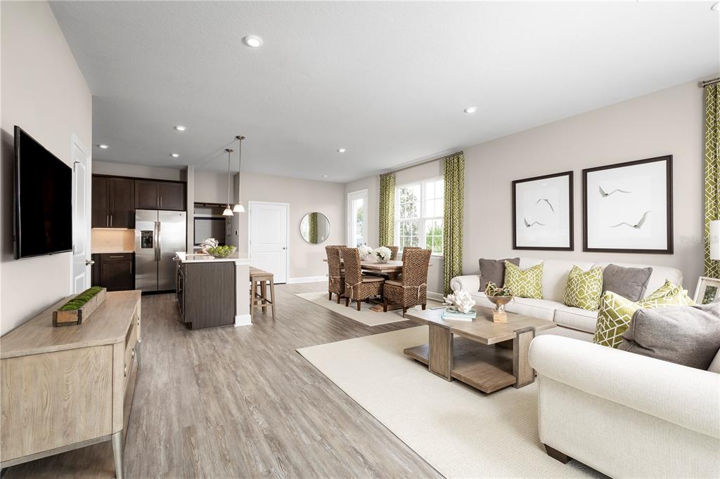 An open-concept living and dining area features light wood flooring, neutral walls, and modern furniture — 6692 CEDAR LANDING CIRCLE, LEESBURG, FL