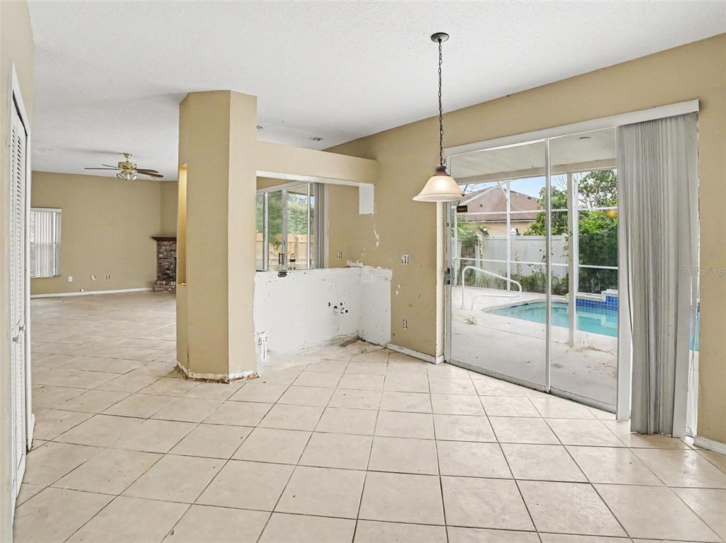 An interior view of a room with tile flooring, a kitchen pass-through, and sliding glass doors — 1268 FOXFORREST CIRCLE, APOPKA, FL