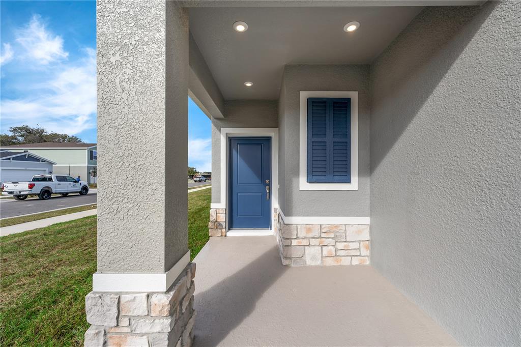 A covered front porch features a blue door, stone accents, and recessed ceiling lighting — 4149 LAVENDER COURT, HAINES CITY, FL