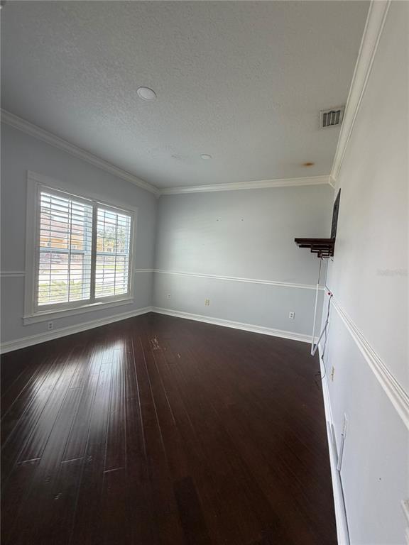 An empty room with dark hardwood floors, light gray walls, and a large window — 3212 MERRICK AVENUE, ROCKLEDGE, FL