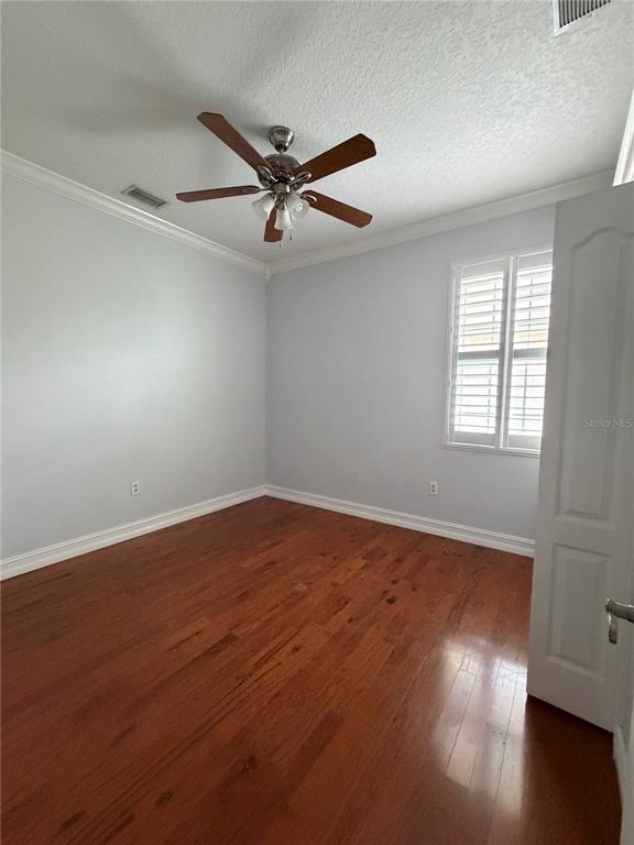 An empty bedroom features light gray walls, hardwood flooring, a ceiling fan, and plantation shutters — 3212 MERRICK AVENUE, ROCKLEDGE, FL
