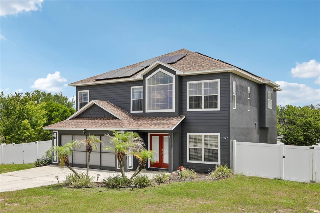 A two-story house with dark gray siding, a red front door, and solar panels — 13247 CASA VERDE CIRCLE, ASTATULA, FL