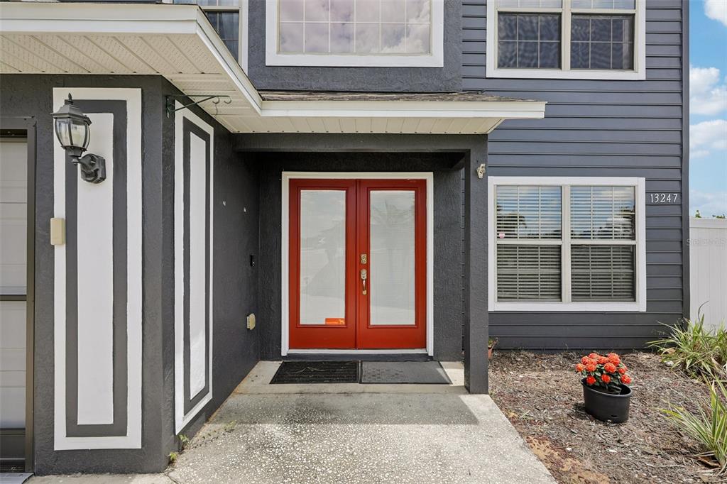 A dark gray house exterior features a bright red double front door and a concrete porch — 13247 CASA VERDE CIRCLE, ASTATULA, FL
