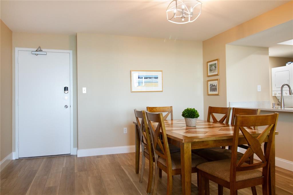 A dining area with a wooden table, six chairs, light-colored walls, and wood-look flooring — 440 S GULFVIEW BOULEVARD UNIT 1002, CLEARWATER BEACH, FL