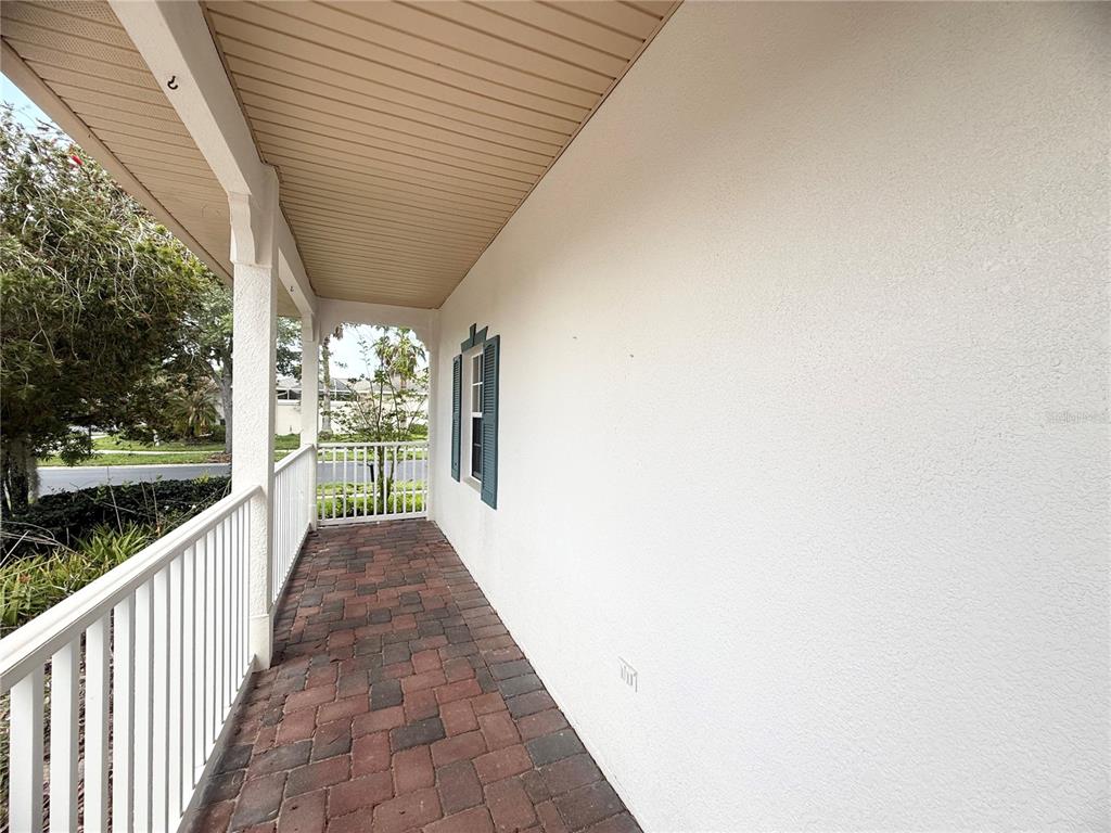 A covered porch features brick pavers, a white railing, and a plain exterior wall — 130 PRIMA DRIVE, KISSIMMEE, FL