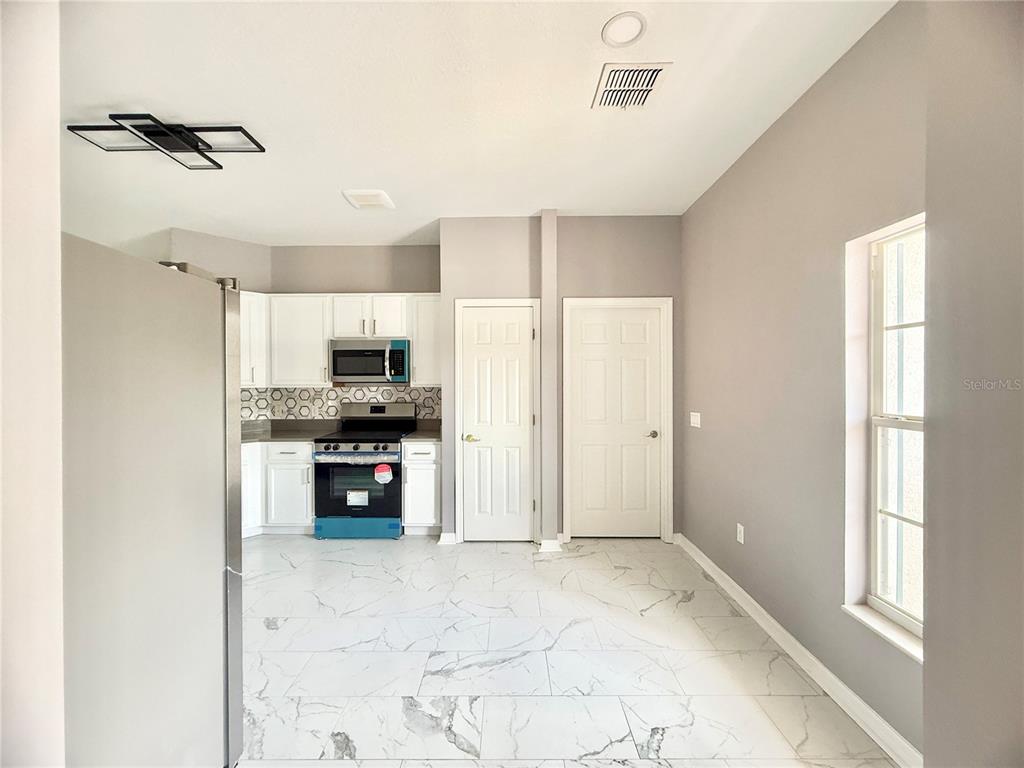 A kitchen with white cabinets, stainless steel appliances, and white marble-patterned tile flooring — 130 PRIMA DRIVE, KISSIMMEE, FL