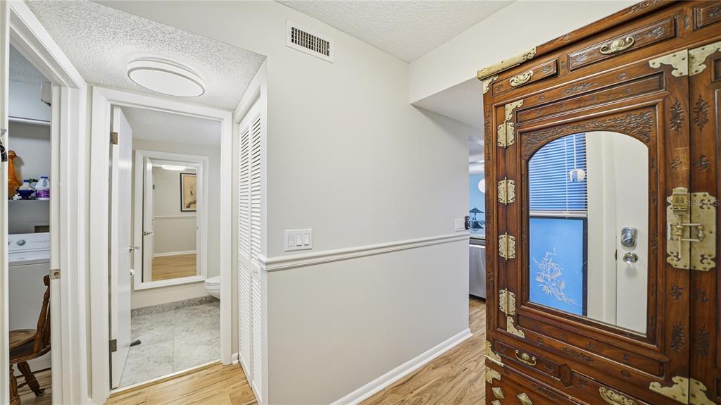 A hallway with wood-look flooring leads to a bathroom and a laundry closet — 890 A1A BEACH BOULEVARD UNIT 31, ST AUGUSTINE, FL