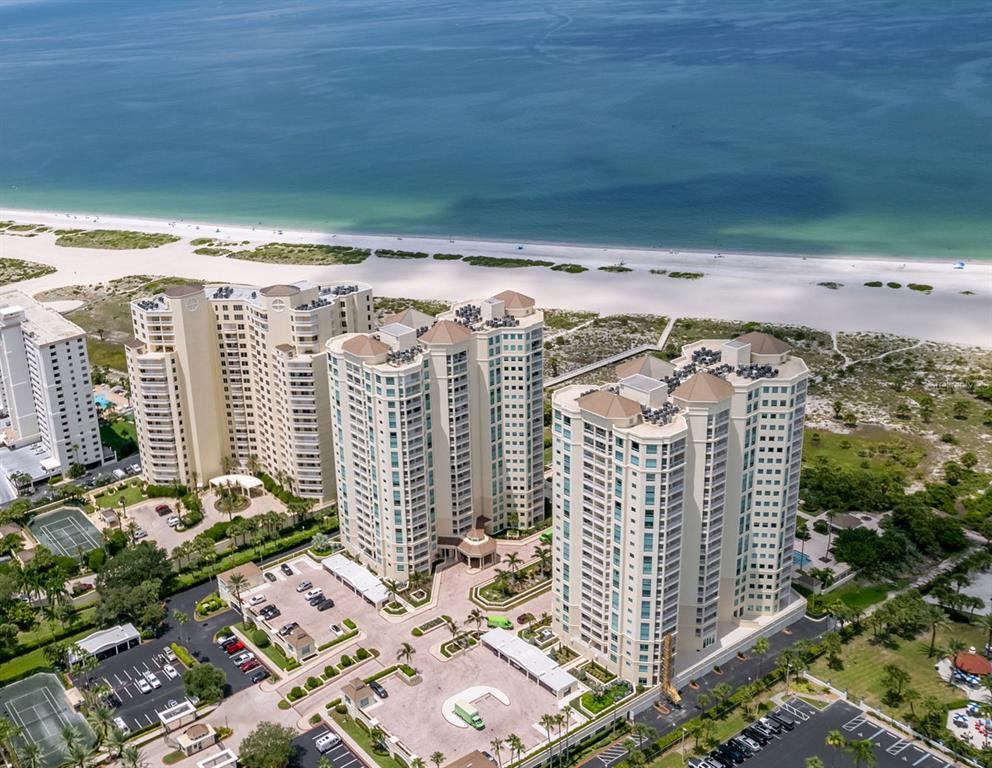 An aerial view shows three tall residential towers situated along a sandy beach and ocean — 1170 GULF BOULEVARD UNIT 2203, CLEARWATER BEACH, FL