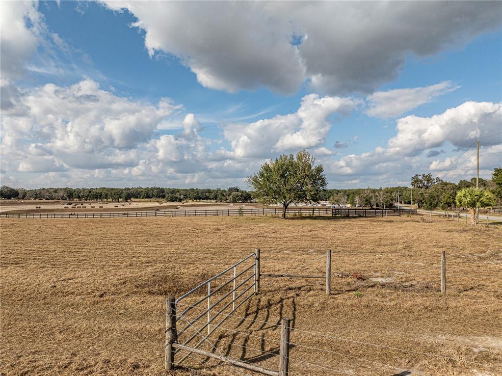 A metal gate opens into a large, dry pasture with a single tree and fencing — COUNTY ROAD 101, OXFORD, FL