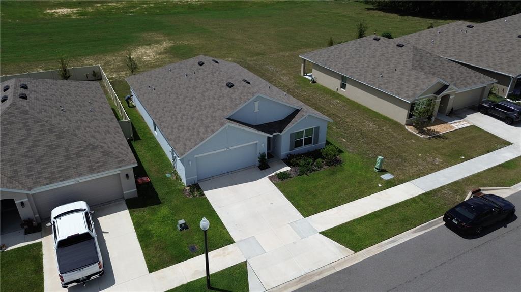 An aerial view shows a light blue single-story house with a driveway and two parked cars — 4728 SW 85TH PLACE, OCALA, FL