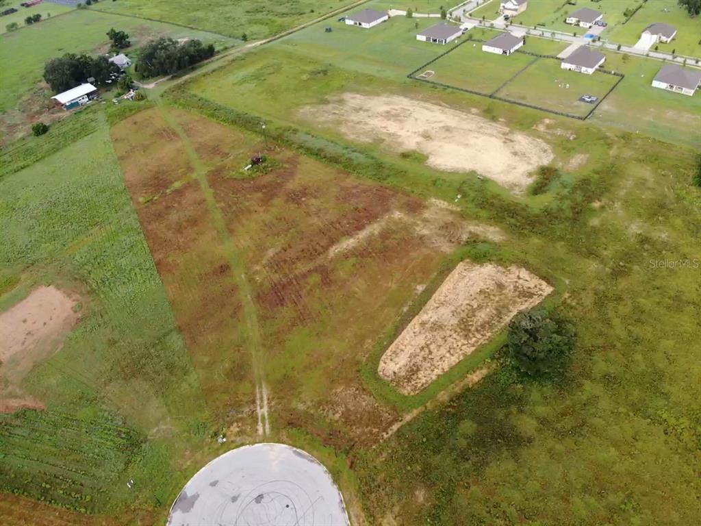 An aerial view shows a vacant, grassy lot with a cul-de-sac and nearby houses — 10016 WHITE EGRET DRIVE, THONOTOSASSA, FL