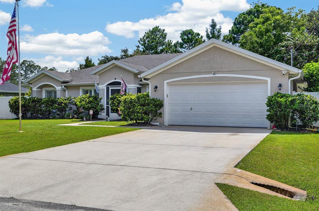 A single-story house with a beige exterior, a two-car garage, and a front lawn — 16 SEVEN CHAMPIONS PATH N, PALM COAST, FL