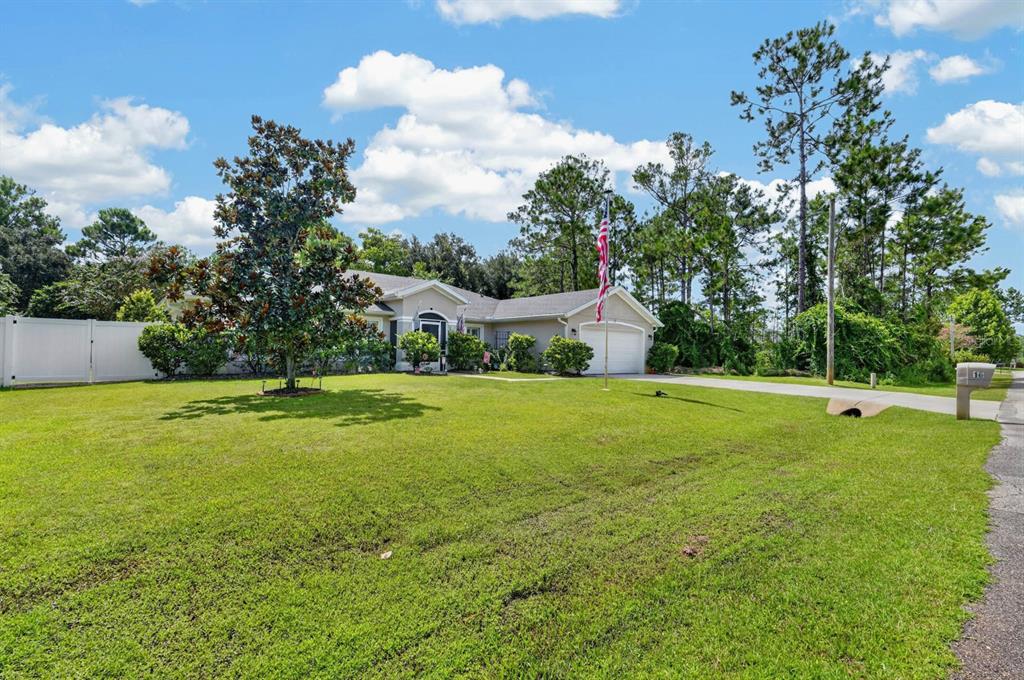 A single-story house with a two-car garage, a large front lawn, and a flagpole — 16 SEVEN CHAMPIONS PATH N, PALM COAST, FL