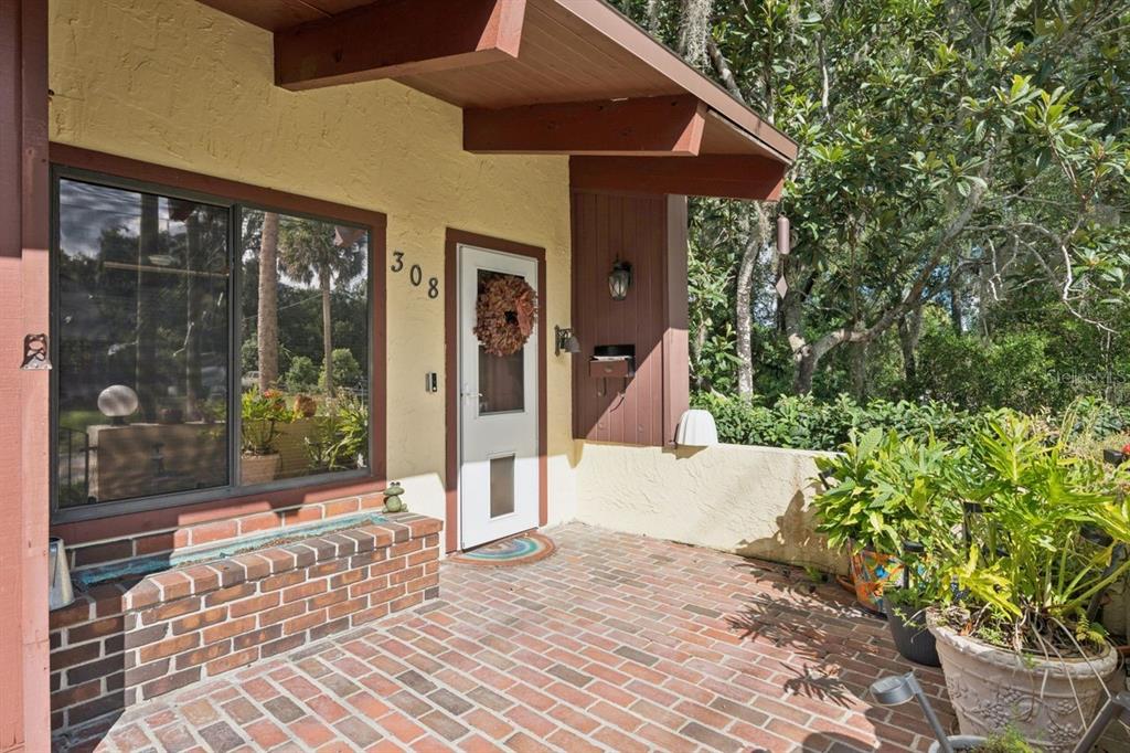 A brick-floored porch features a front door with a wreath and a large window — 308 N GARFIELD AVENUE, DELAND, FL
