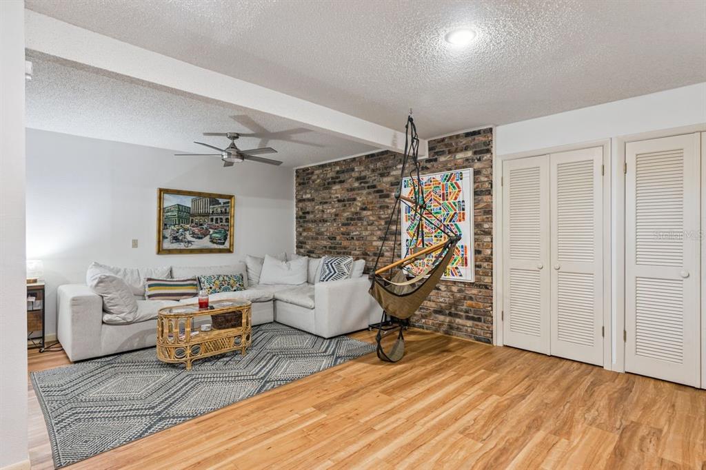 A living room features a white sectional sofa, a hanging chair, and an exposed brick wall — 308 N GARFIELD AVENUE, DELAND, FL