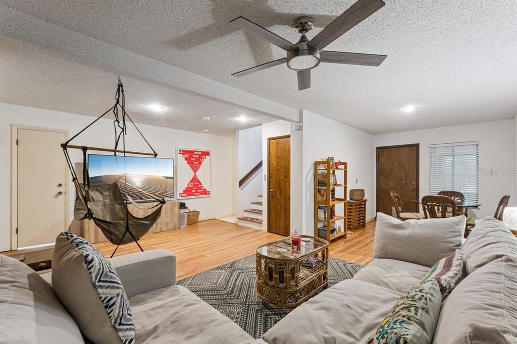 A living room features a hanging chair, a sectional sofa, a coffee table, and stairs — 308 N GARFIELD AVENUE, DELAND, FL