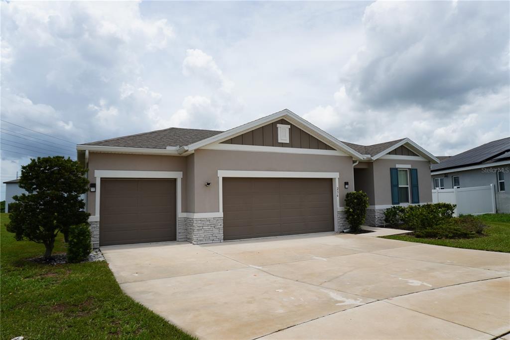 The exterior rear view of a beige single-story house with a large grassy backyard — 236 HILLCREST DRIVE, DUNDEE, FL