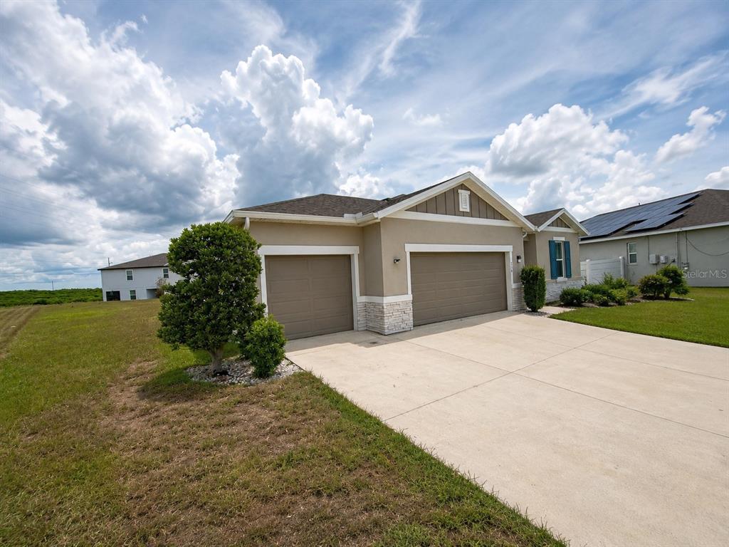 The exterior of a beige house with a covered patio and a large grassy yard — 236 HILLCREST DRIVE, DUNDEE, FL