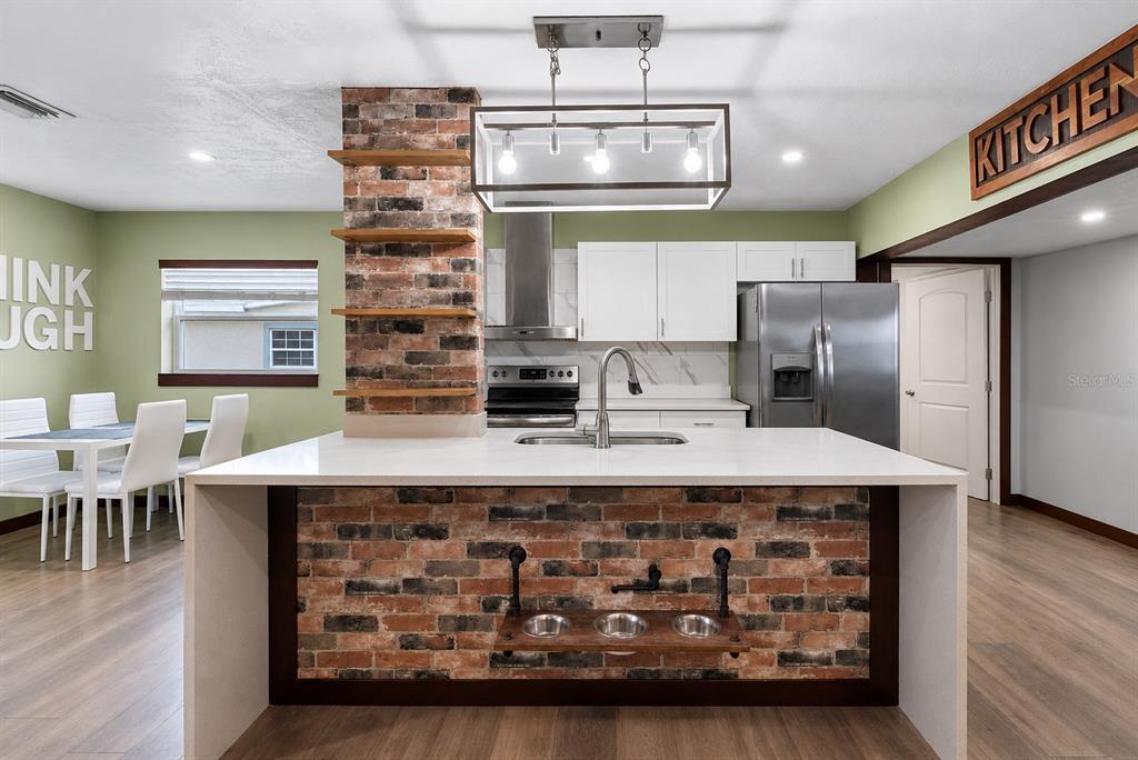 A kitchen features a brick-faced island with a built-in pet feeding station and white cabinetry — 1428 MAURY ROAD, ORLANDO, FL
