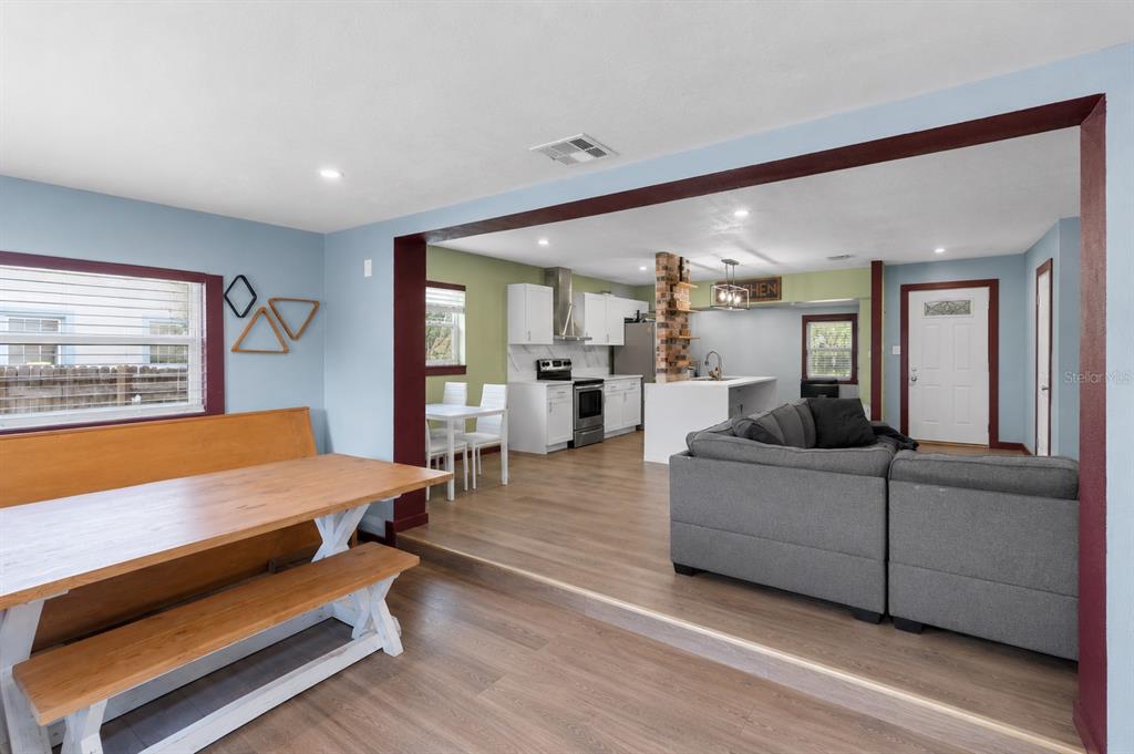 A dining area with a wooden bench table overlooks a kitchen and living room space — 1428 MAURY ROAD, ORLANDO, FL