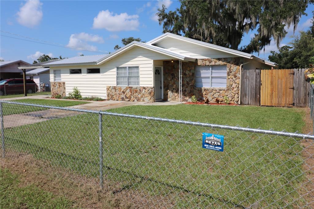 A single-story house with a carport, stone accents, and a concrete driveway under a sunset — 2620 HOWARD STREET, MULBERRY, FL