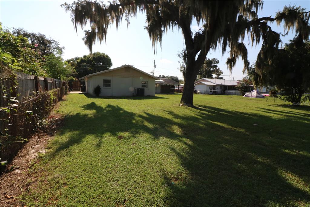 An empty room features wood-look flooring, cream-colored walls, a window with curtains, and a French door — 2620 HOWARD STREET, MULBERRY, FL
