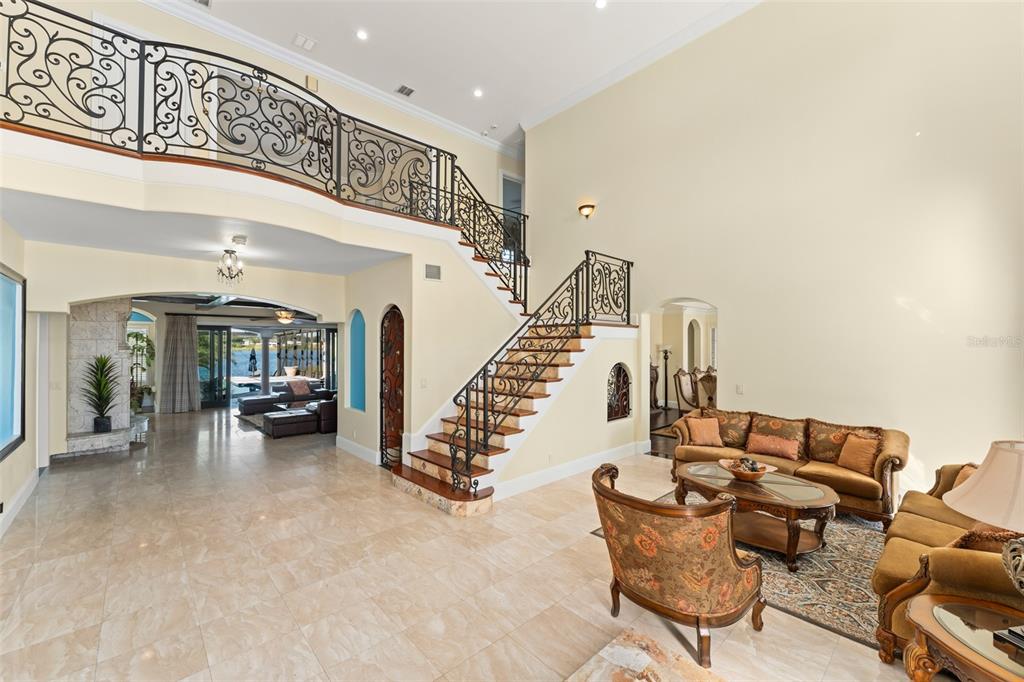 A spacious living room features a grand staircase with ornate iron railings and tile flooring — 9575 WESTOVER ROBERTS ROAD, WINDERMERE, FL