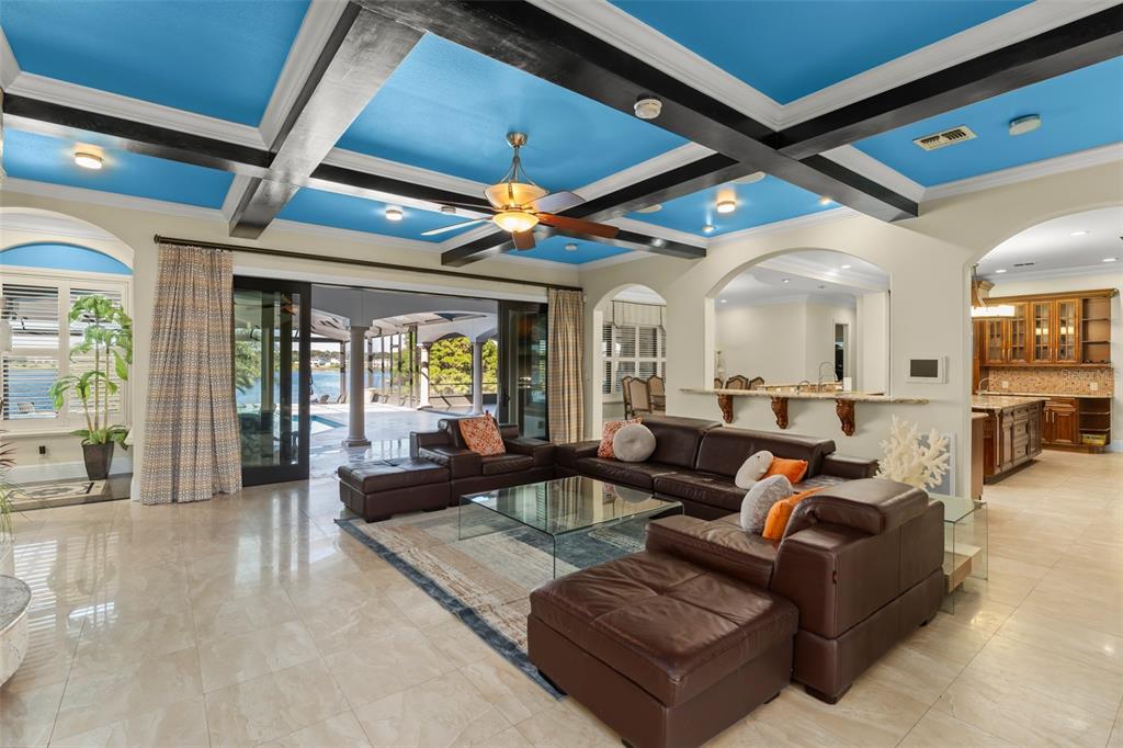 A living room features a bright blue coffered ceiling, dark wood beams, and sliding glass doors — 9575 WESTOVER ROBERTS ROAD, WINDERMERE, FL
