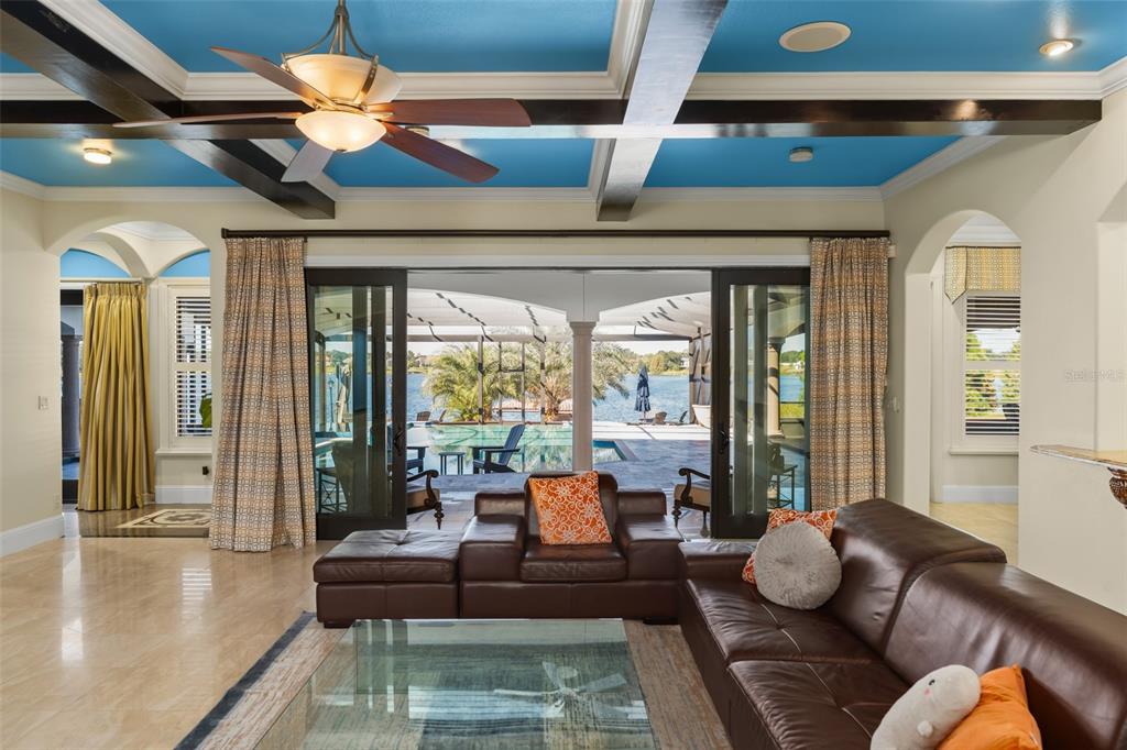 A living room with a blue coffered ceiling, leather furniture, and sliding doors opening to a pool — 9575 WESTOVER ROBERTS ROAD, WINDERMERE, FL